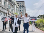 被坑3千萬元，李姓受害人（右）和郭律師（左）在建案前舉牌抗議集團犯罪手法。（照片記者攝）